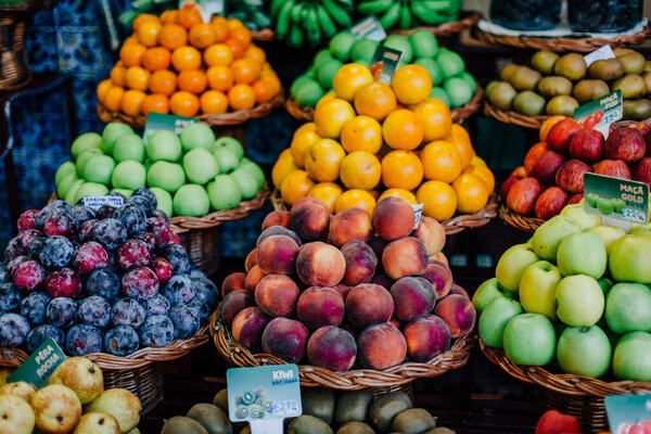 Funchal - Madeira, 20.09.2019. Fruits in baskets on the counter. Apples, plums, peaches.