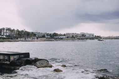 Paphos, yu... 30.04.2020. Otelleri ve evleri olan Akdeniz kıyıları. Gökyüzü bulutlu, denizde dalgalar var. Fırtına şehre yaklaşıyor..