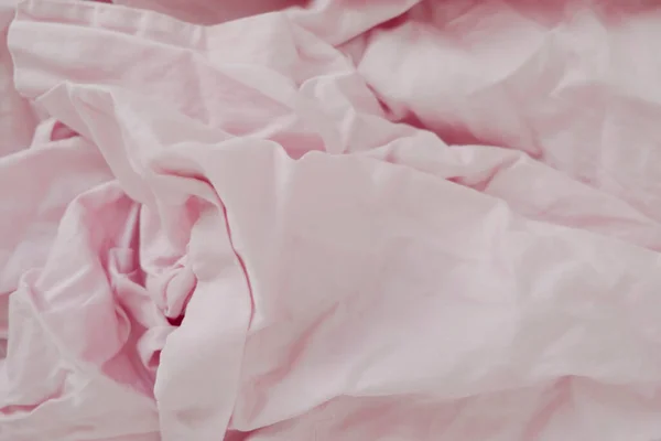 Crumpled pastel pink bed linen for light background.