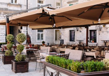 Masaları, sandalyeleri ve büyük çadırları olan bir kafe. Açık havada yaz. 