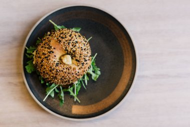 Siyah tabakta susamlı simit, humus ve sebze. Yukarıdan görüntüle.