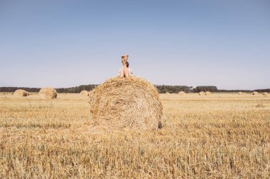 Yaz tarlasında saman balyasında dinlenen bir kız. Hasat, yazın sonunda. Kırsal kesimde yavaş yaşam.
