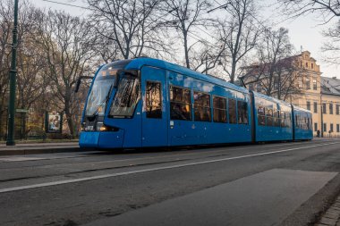 Modern bir tramvay Polonya 'nın merkezindeki bir parktan geçiyor.