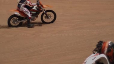Motosikletliler çölde kum tepesinde gezerler.