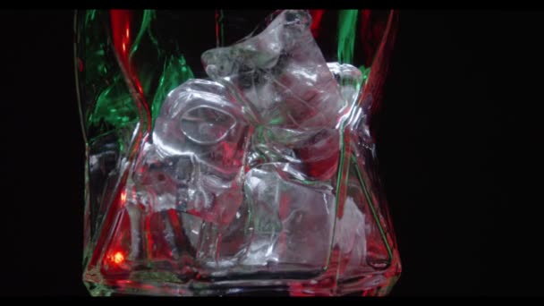 Vaso de vidrio con hielo en una barra en la que se vierte líquido — Vídeos de Stock