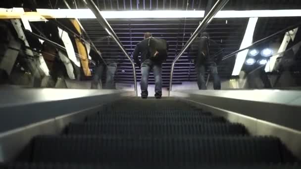 En man står på en rulltrappa och klättrar till toppen för en konferens — Stockvideo