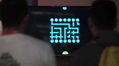 Erkekler bir konferansta iş merkezinde oyun oynayan bir ekrana bakıyorlar.