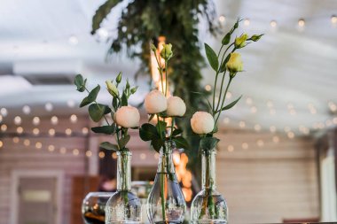 Düğün masası süslemeli boho. Detaylarla süslenmiş, cam vazolarda çiçek şakayıkları düzenlenmiş.