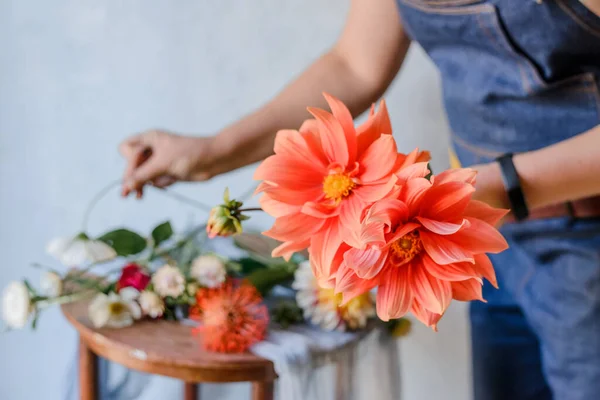 Woman making a bouquet from fresh garden peonies. Creating a spring bouquet with red and oprange flowers.
