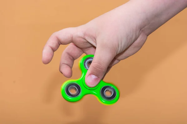 Boy playing with fidget spinner gadget. The fidget spinner is a toy, a small spit, the rotating body is pivoted on a ball bearing which allows it to rotate on the axis of rotation.