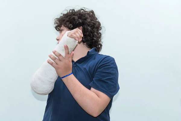 Boy with broken arm, plaster on arm as therapy. Close up of a young man\'s white long arm plaster / fiberglass cast covering the wrist, arm, and elbow after an skating accident.