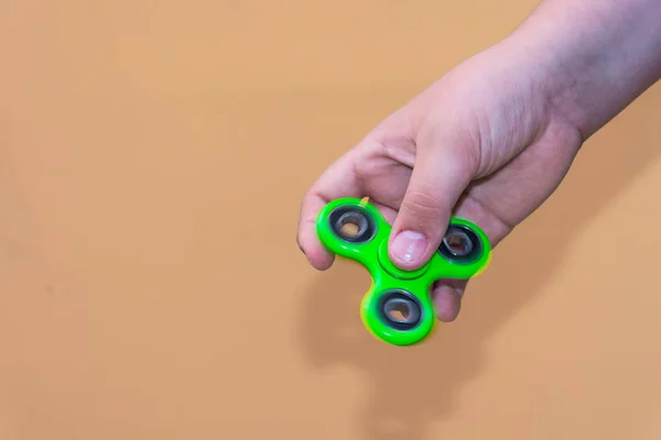 Boy playing with fidget spinner gadget. The fidget spinner is a toy, a small spit, the rotating body is pivoted on a ball bearing which allows it to rotate on the axis of rotation.