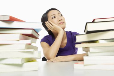 Etrafı kitaplarla çevrili, sıkılmış görünüyor.