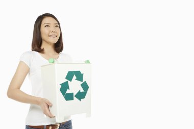 Elinde plastik şişelerle dolu bir geri dönüşüm kutusunu tutan kadın.