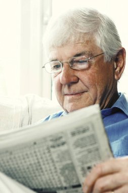 Gazete okuyan gözlüklü yaşlı bir adam.