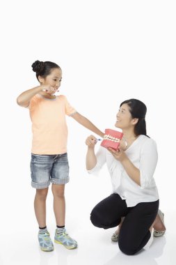 Anne, kızına diş fırçalamayı öğretiyor.