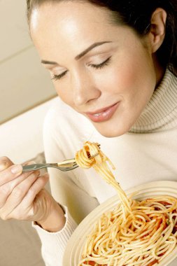 Bir kase spagetti yiyen bir kadın.