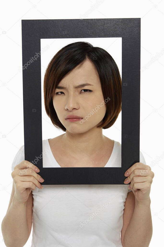 Woman holding up a black picture frame, looking angry