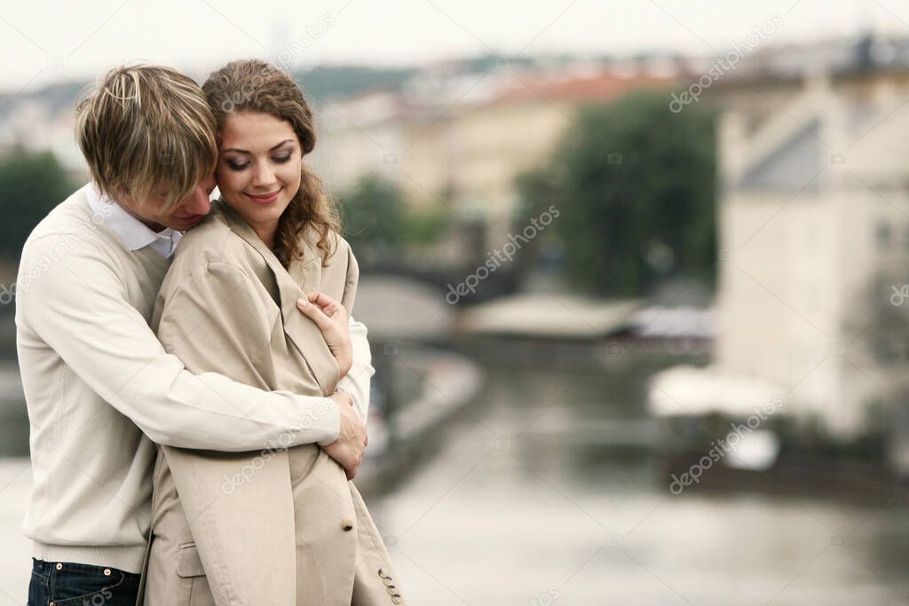 A guy warming up his girlfriend by hugging her from the back