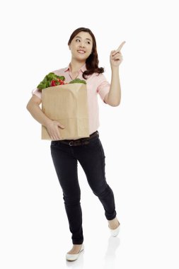 Woman with groceries pointing to the left clipart