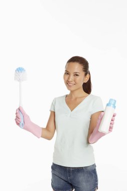 Elinde deterjan şişesi ve fırça tutan bir kadın.