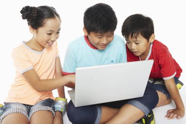 Birlikte dizüstü bilgisayar kullanan üç çocuk.