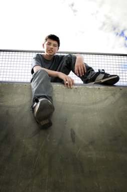 Kaykay parkında oturan bir çocuk.