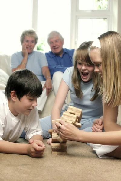 Old Couple Sitting Couch Watching Grandchildren Playing Building Blocks Floor — Stock Photo, Image