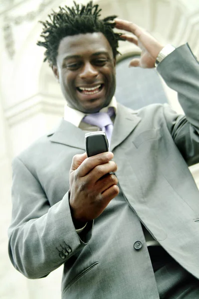 A African American man in business suit laughing at the message he received