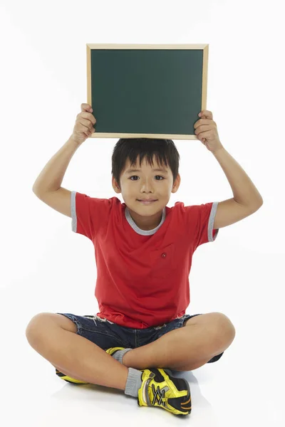 男孩坐着 举起一块黑板 — 图库照片