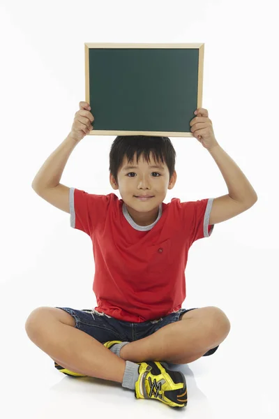 Junge Sitzt Und Hält Eine Tafel Hoch — Stockfoto