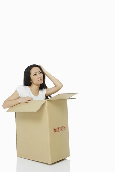 Mulher Sentada Dentro Uma Caixa Papelão Parecendo Confusa — Fotografia de Stock
