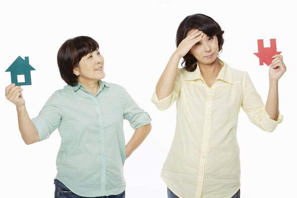 Women with different facial expressions holding up a cut out house