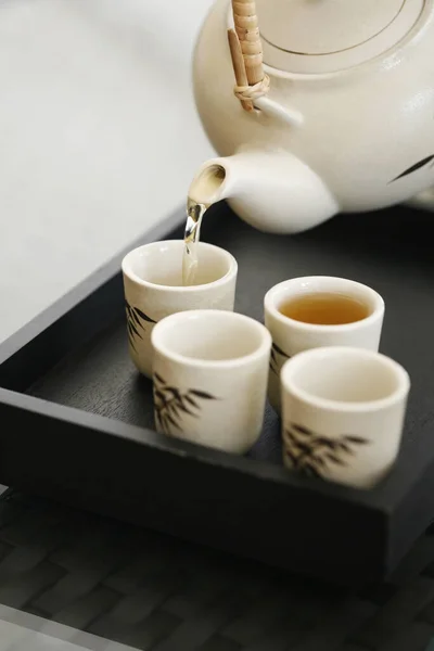 Pouring tea into teacups on tray