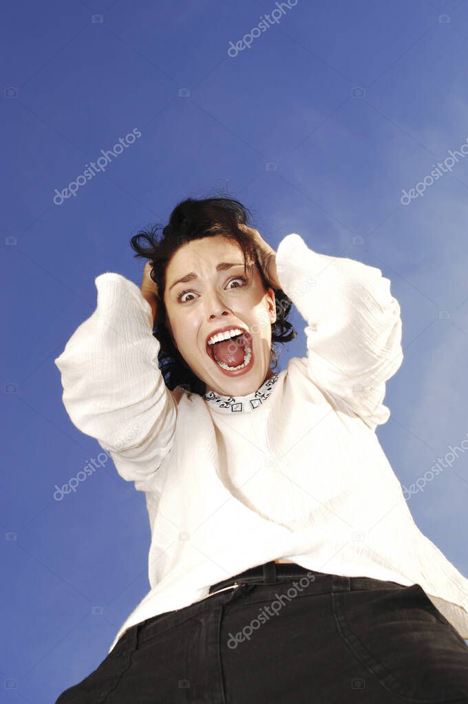 Woman screaming hysterically against blue sky