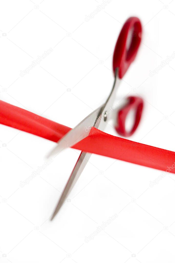 Scissors cutting through a red ribbon