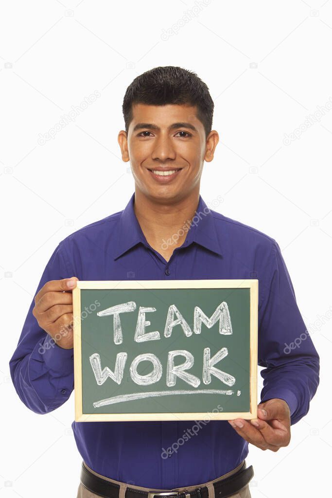 Businessman holding up a blackboard with 'Team work' written on it