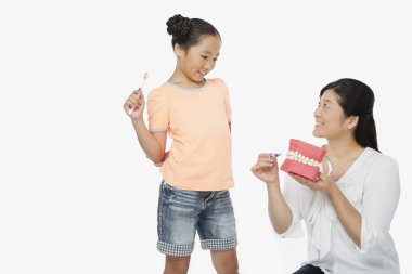 Anne, kızına diş fırçalamayı öğretiyor.