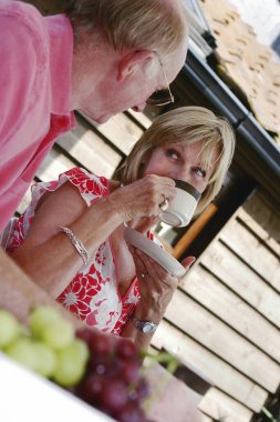 Evli bir çift arka bahçede sohbet edip içiyor.