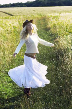 Sahada koşan kovboy şapkalı bir kadın.