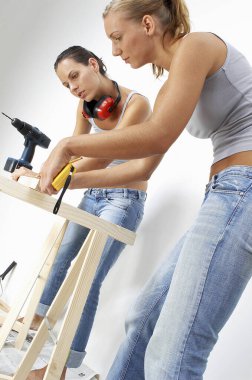 Bir kadın, arkadaşının odunu ölçmesine yardım ediyor.