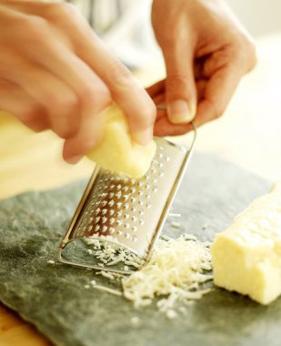 Şef parmesan peynirini kayrak zeminde rendeliyor.