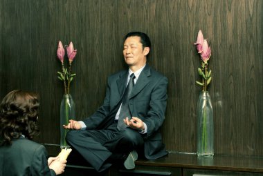 Meditasyon yapan bir adamın önünde dua eden bir kadın.