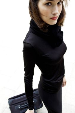 Bir kadın seyahat çantasını çekiyor.