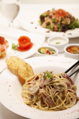 Arka planda spagetti carbonara ve salata