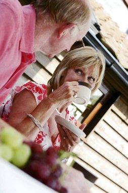 Evli bir çift arka bahçede sohbet edip içiyor.