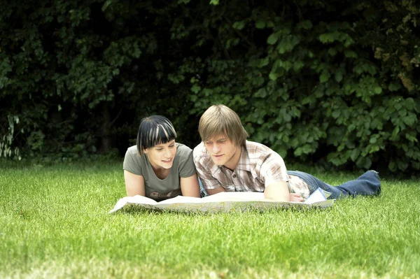 Couple Lying Grass Analyzing Map — Stockfoto