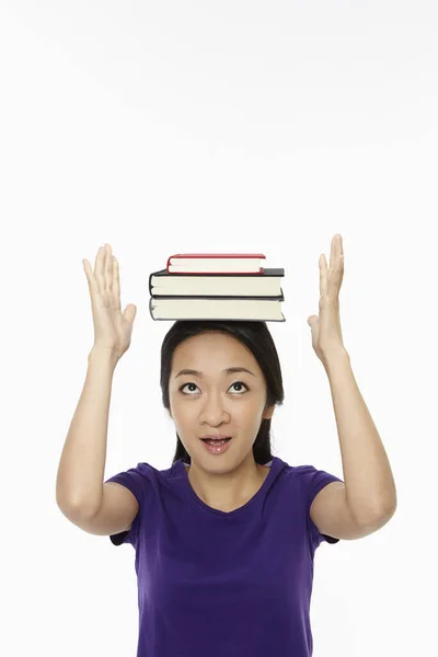 女人把头靠在一堆书上保持平衡 — 图库照片