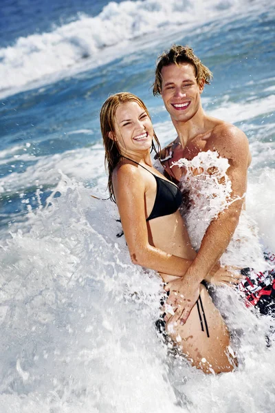 波に打たれながら楽しむ二人の夫婦 — ストック写真