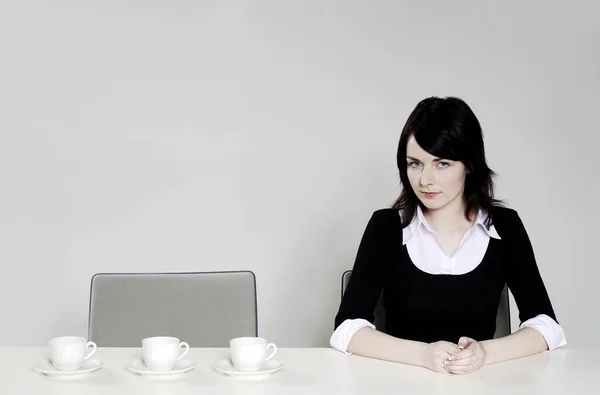 Geschäftsfrau Sitzt Neben Drei Arrangierten Tassen — Stockfoto